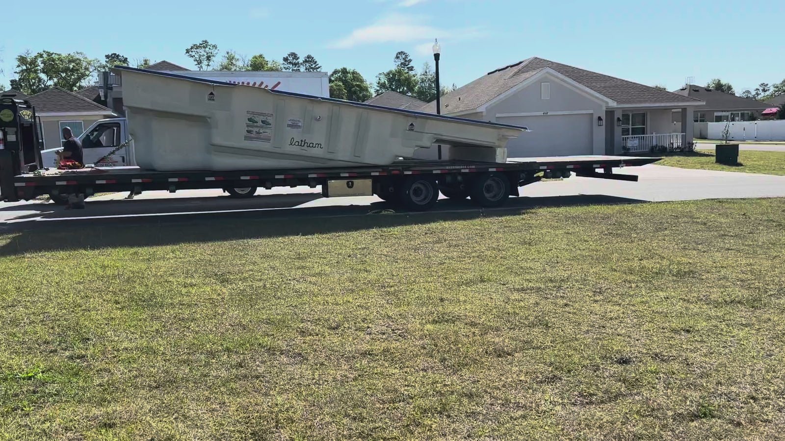A Latham fiberglass pool shell arriving in one piece on a flatbed trailer for a Cool Pool of Florida install